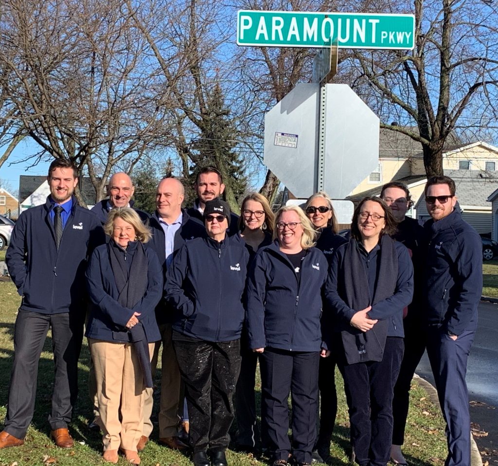 Level FA team in front of Paramount pkwy road sign