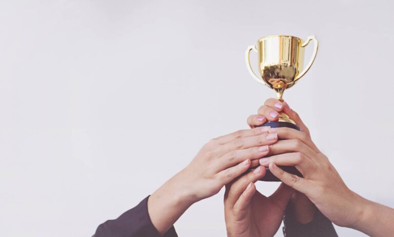 Many hands holding a trophy